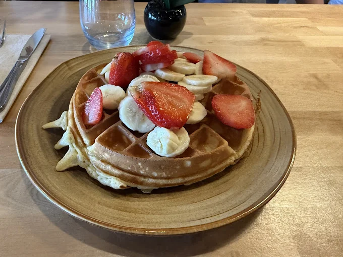 Belgian waffle topped with strawberries, banana slices and whipped cream