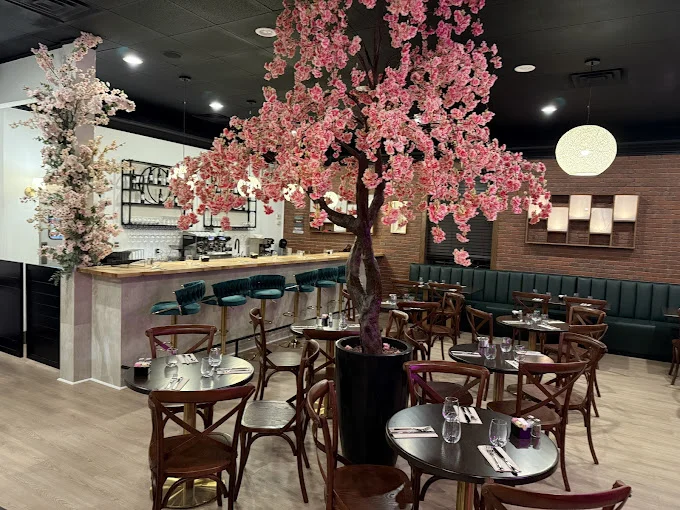 Morning Bloom interior with a large pink blossom tree, bar seating, green booths and pendant lights