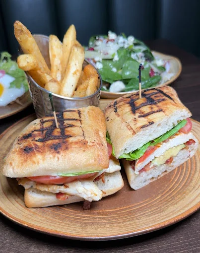 Grilled panini halves with French fries and a side salad