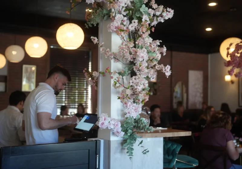 Morning Bloom team member at the counter beneath a blossom installation while guests dine