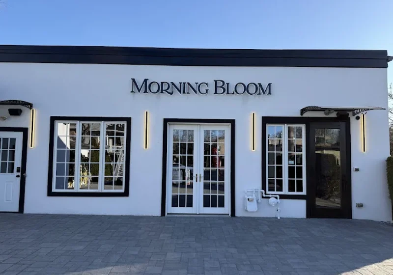 White storefront of Morning Bloom on West Allendale Avenue with black-framed windows and French doors